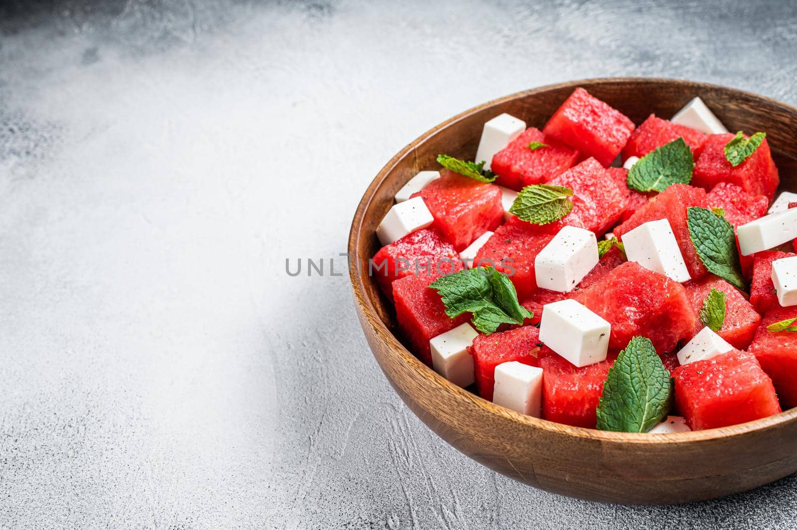 Watermelon Salad with feta cheese in a wooden plate. White background. Top view. Copy space.