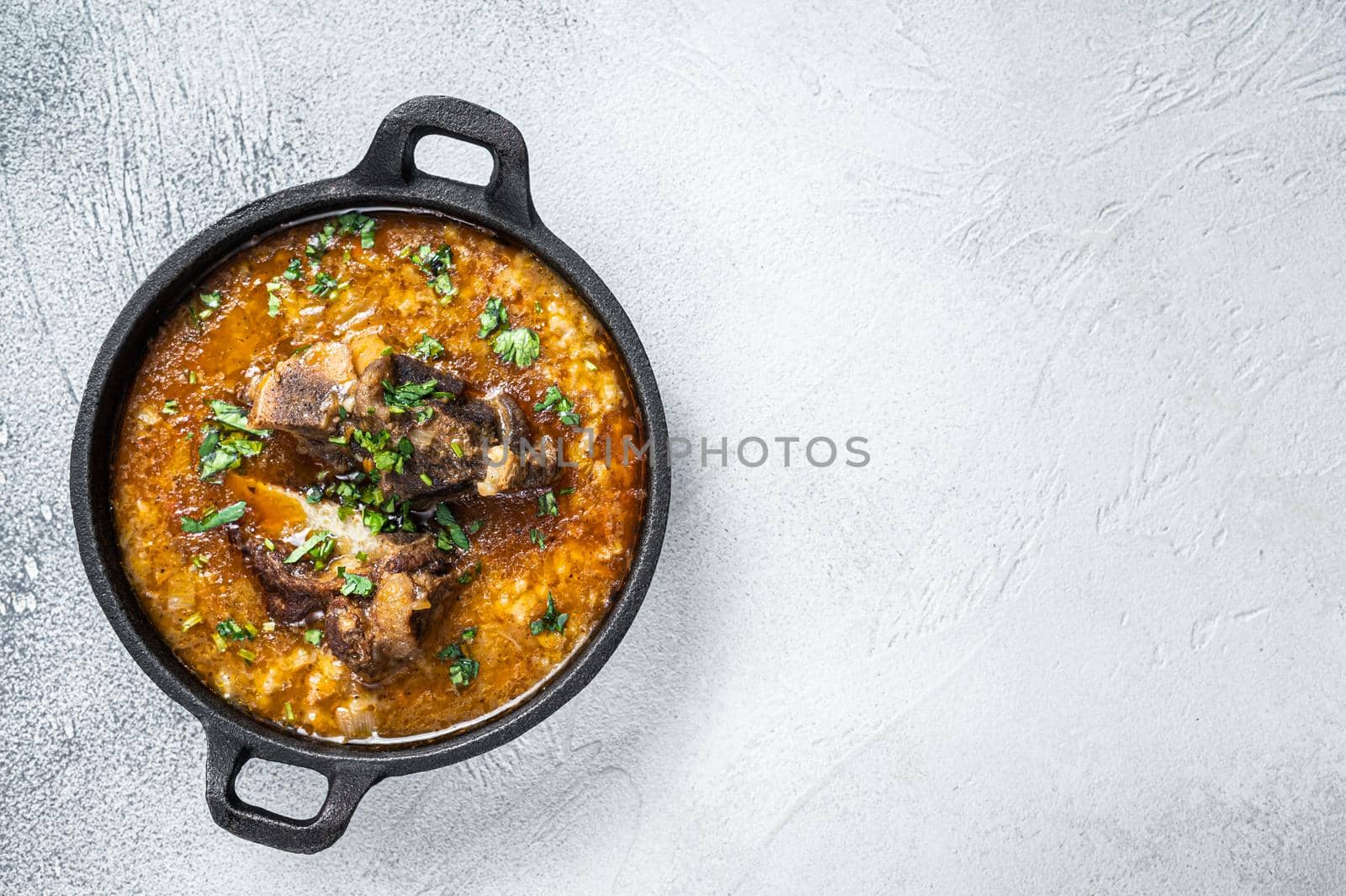 Kharcho soup with beef meat, rice, tomatoes and spices in a pan. White background. Top view. Copy space by Composter