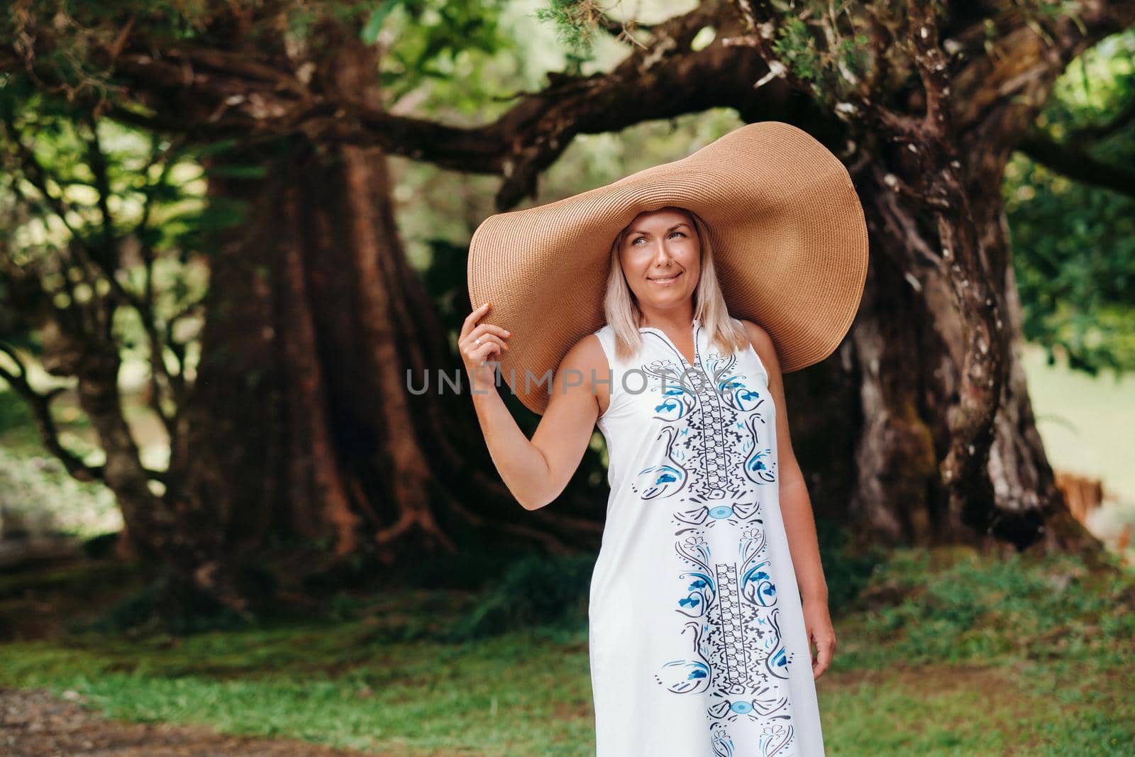 A woman in a large hat and long dress poses on the island of Mauritius. beautiful girl resting on the island of Mauritius.