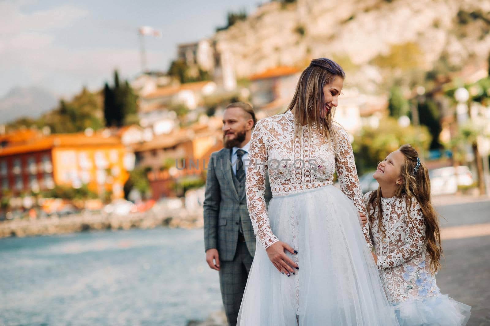 Italy, Lake Garda. Beautiful family on the shores of lake Garda in Italy at the foot of the Alps. Father, mother and daughter in Italy.