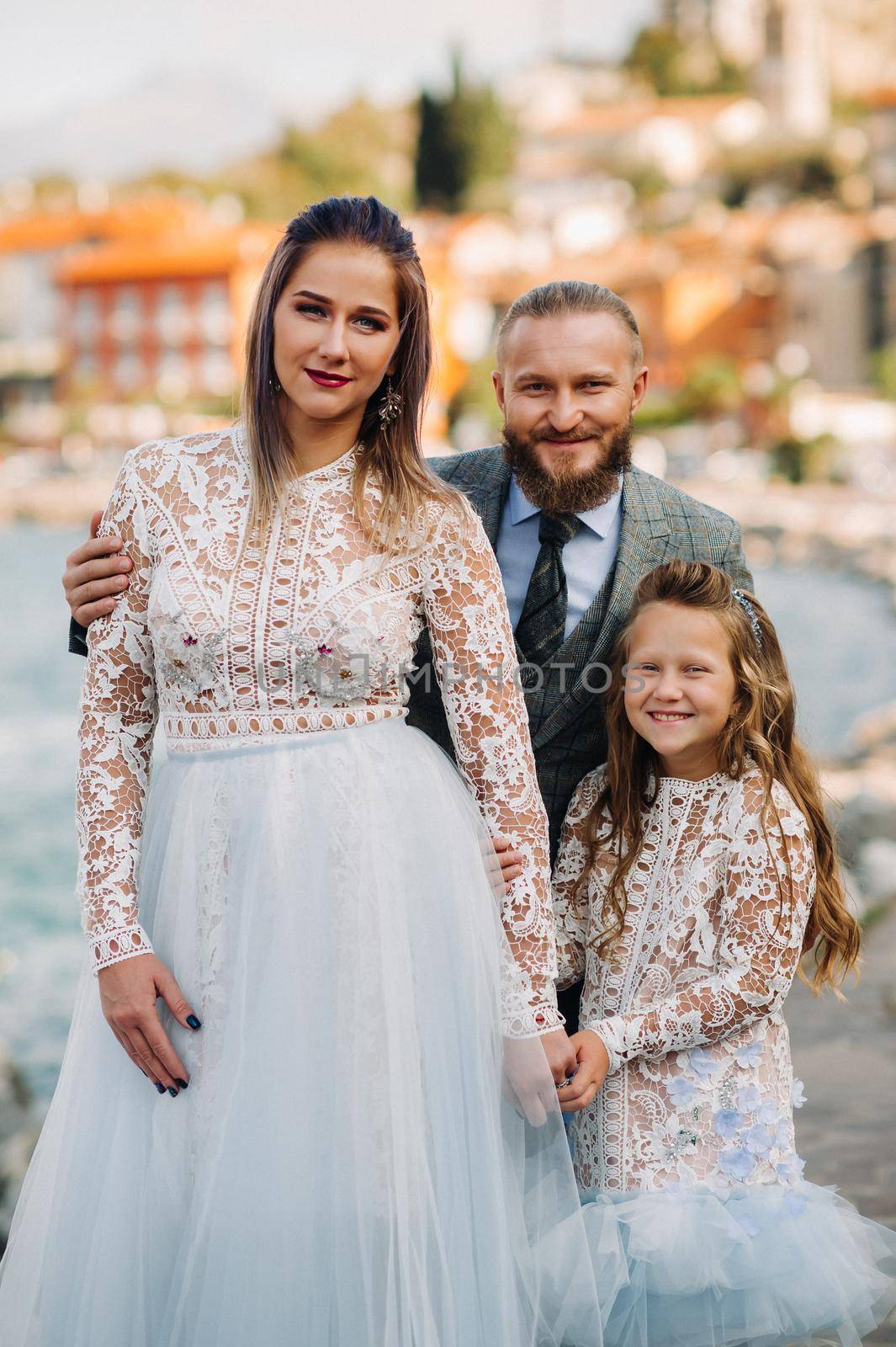 Italy, Lake Garda. Beautiful family on the shores of lake Garda in Italy at the foot of the Alps. Father, mother and daughter in Italy by Lobachad