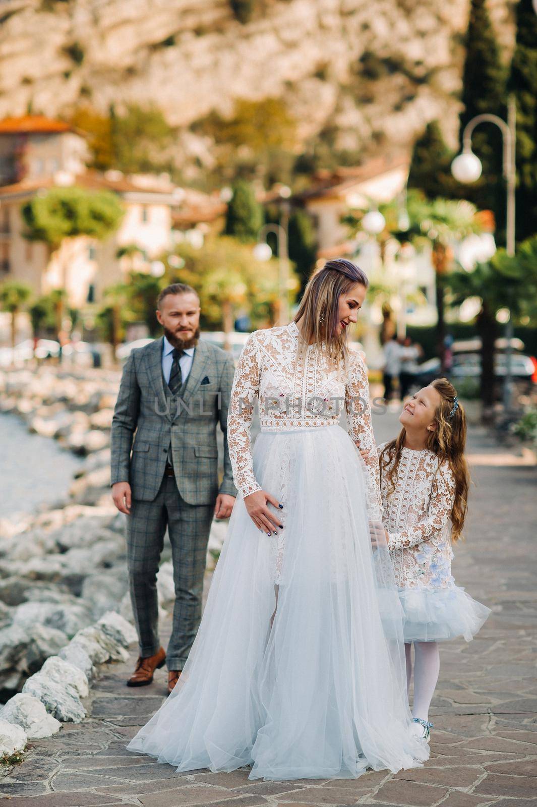 Italy, Lake Garda. Beautiful family on the shores of lake Garda in Italy at the foot of the Alps. Father, mother and daughter in Italy by Lobachad