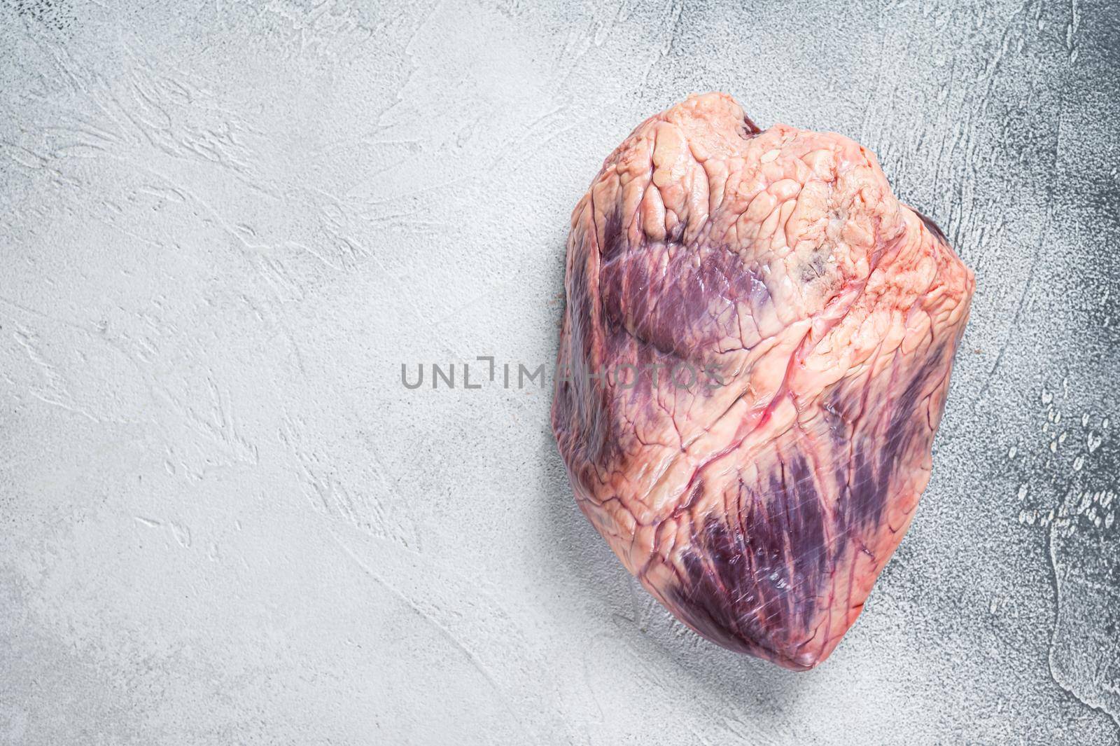 Beef or veal raw heart on a butcher table. White background. Top View. Copy space.
