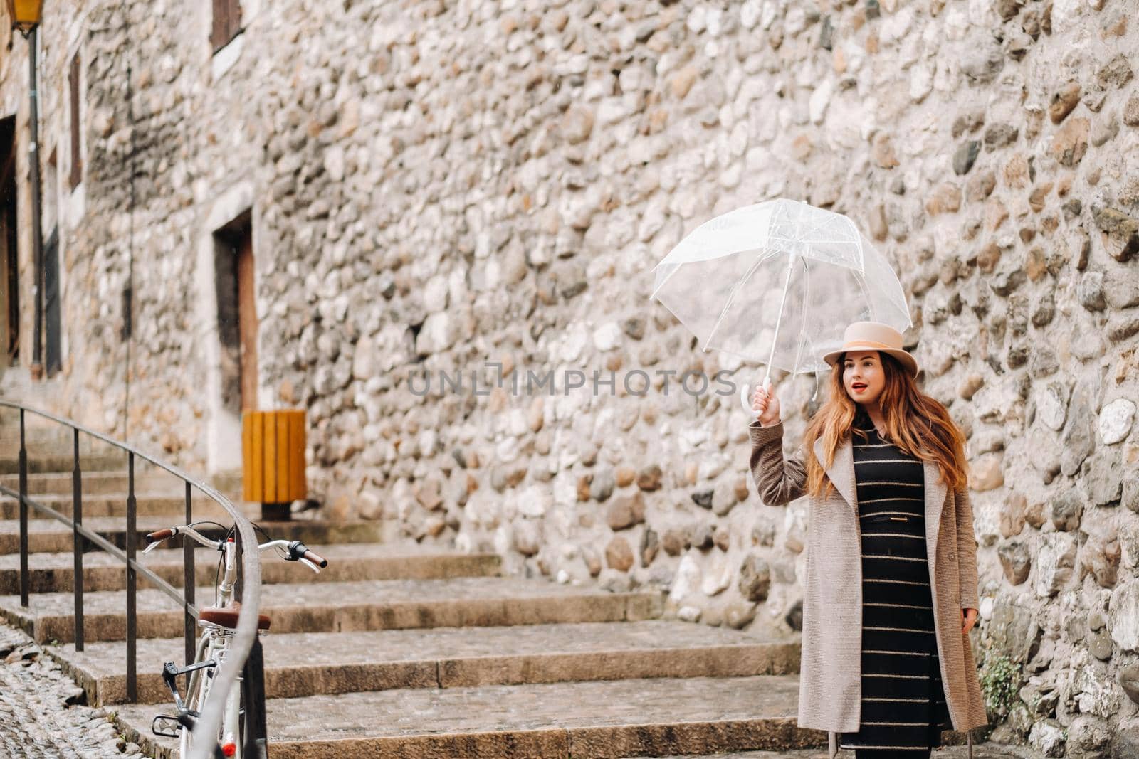 beautiful romantic girl in a coat and hat with a transparent umbrella in Annecy. France. The girl in the hat in France.