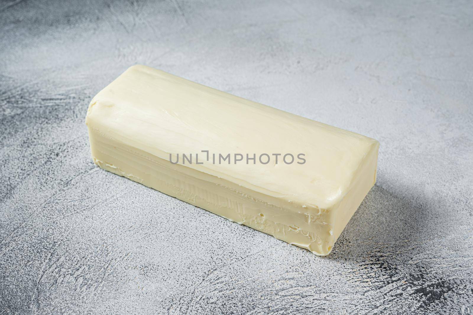 Piece of fresh butter for breakfast on kitchen table. White background. Top view.