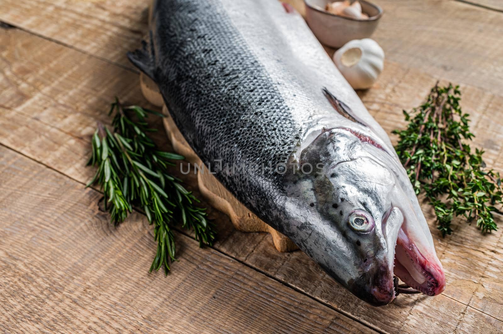 Raw marine salmon fish on a wooden kichen table with herbs. Wooden background. Top view by Composter