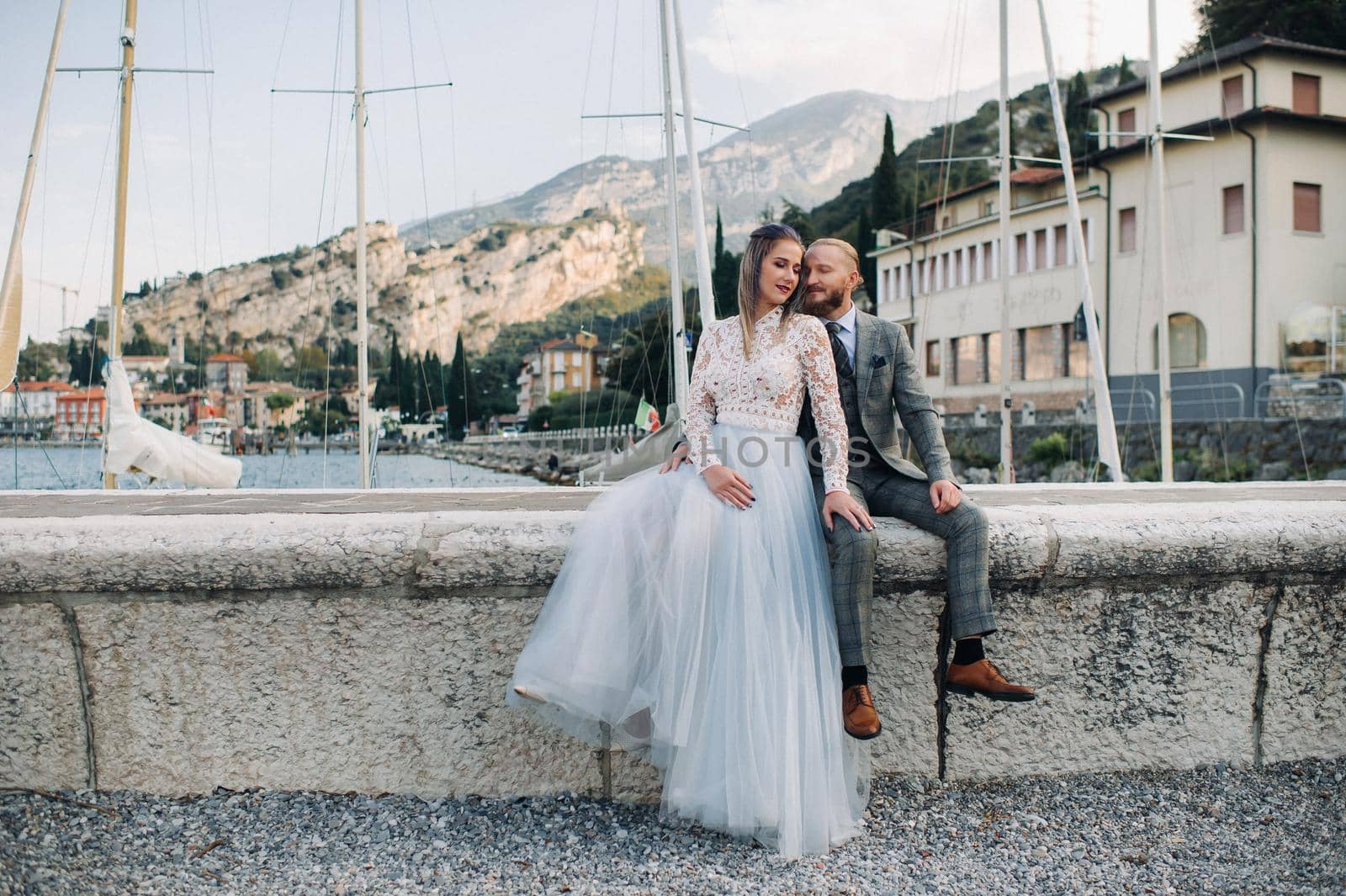 Italy, Lake Garda. A beautiful couple on the shores of lake Garda in Italy at the foot of the Alps.A man and a woman sit on a pier in Italy.