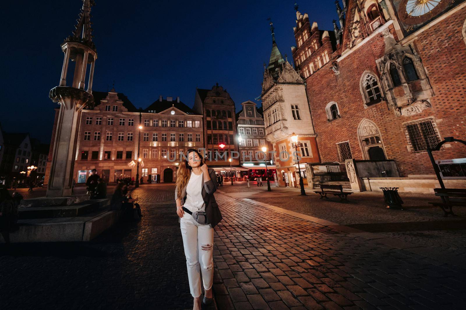 a romantic girl walks in the old town of Wroclaw in the late evening.Walk of a woman in trousers and jacket in the old town of Poland.