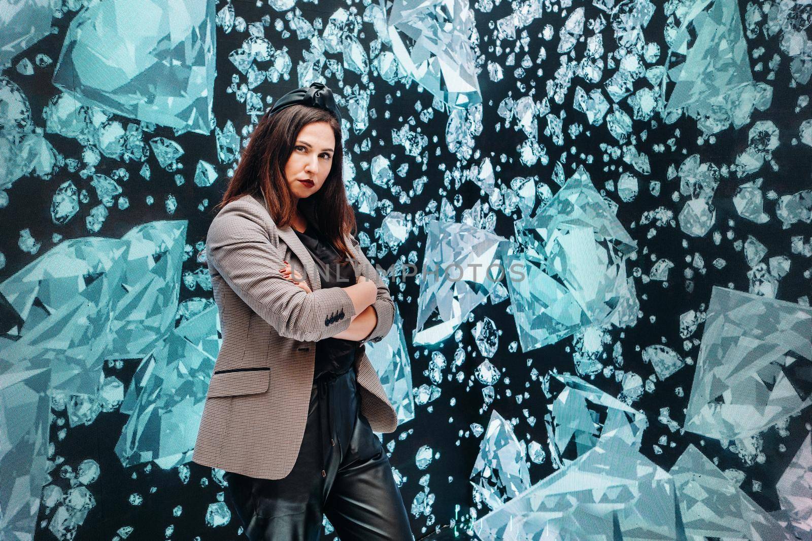 A girl in black pants and a jacket on a background of diamonds.