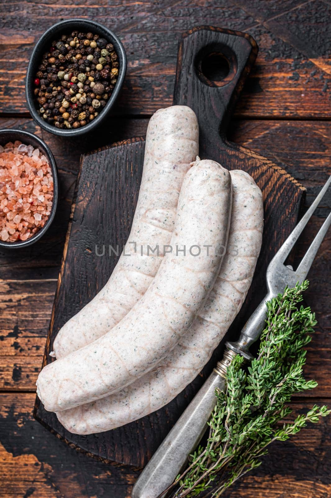 Munich traditional white sausages on a wooden board with thyme. Dark wooden background. Top view by Composter