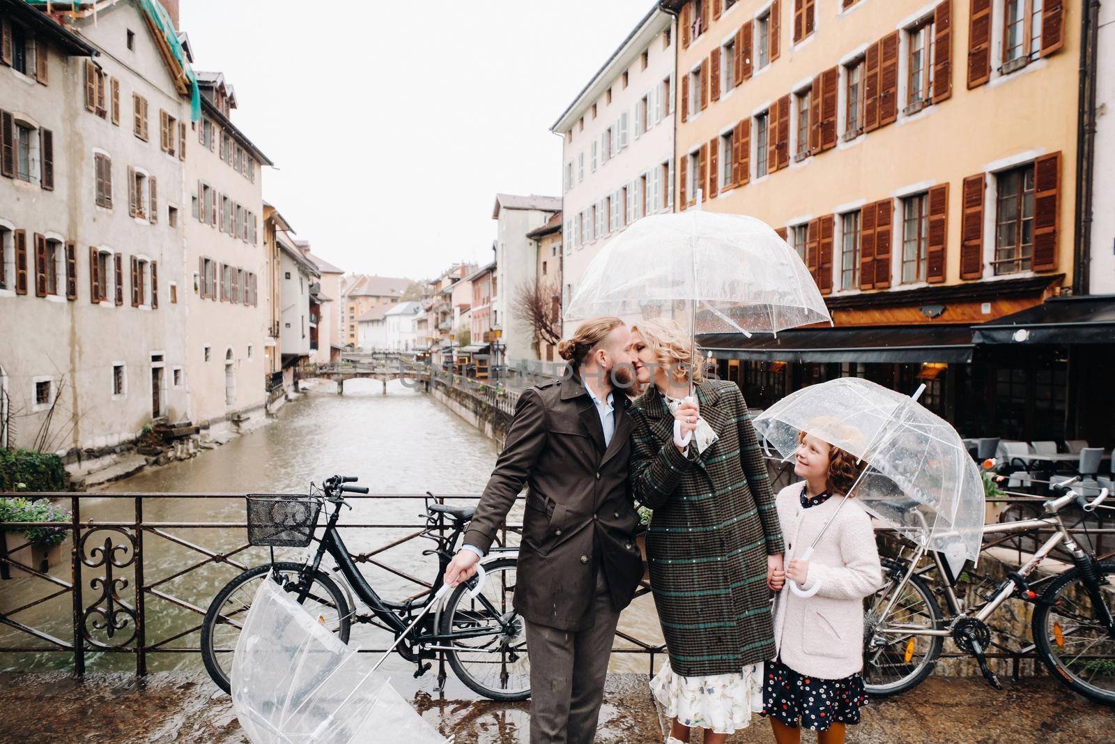 Beautiful family with umbrellas in rainy weather in Annecy. France.Family walk in the rain.