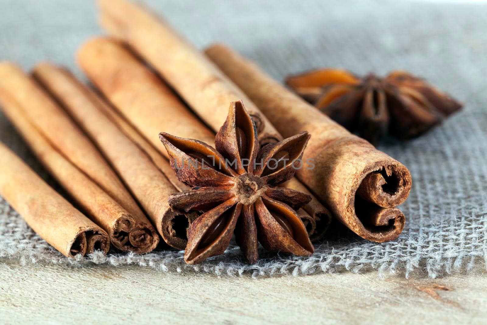 lying on a wooden board and linen tablecloth a few fragrant cinnamon sticks and anise stars, used as spices in cooking, close-up