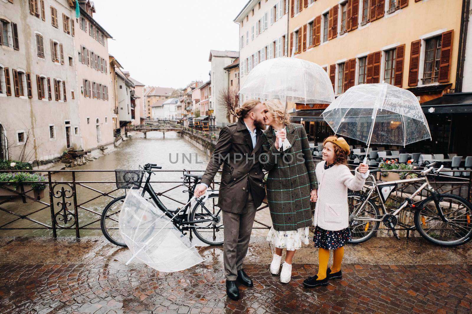 Beautiful family with umbrellas in rainy weather in Annecy. France.Family walk in the rain.