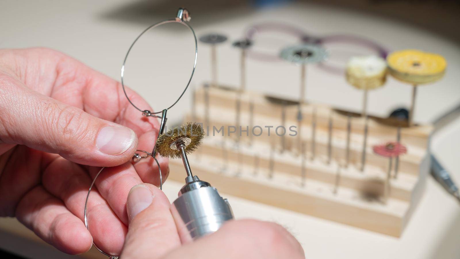 An optician technician polishes the frame of glasses. A professional optician fixes glasses