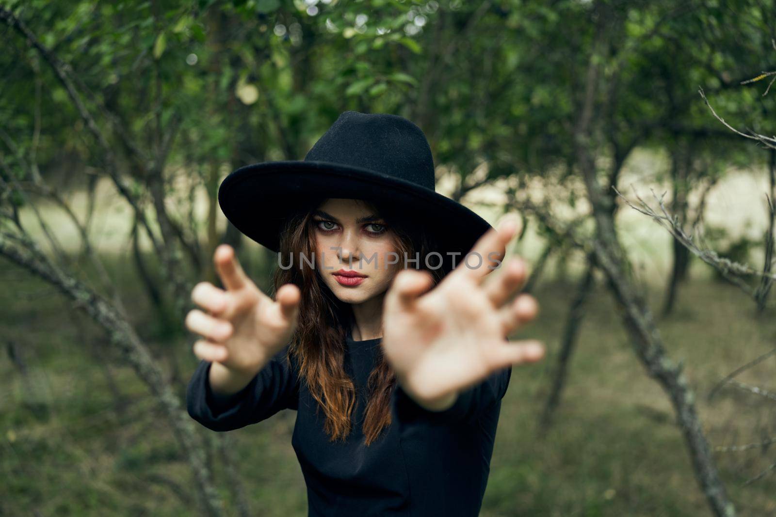 woman in black witch costume in forest nature posing. High quality photo