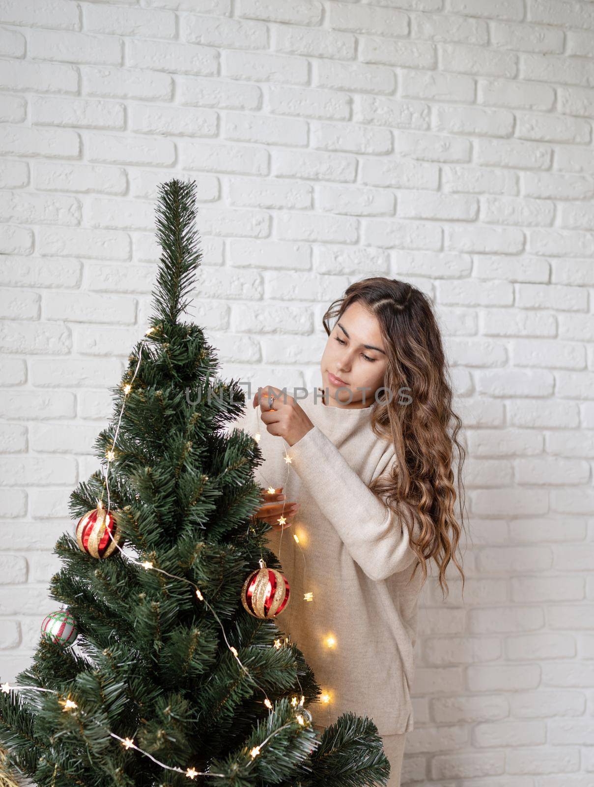 Merry christmas and happy new year. young attractive woman decorating the Christmas tree with fairy lights