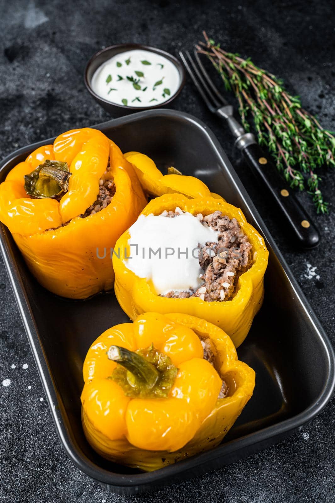 Baked yellow Sweet bell pepper stuffed with beef meat, rice and vegetables. Black background. Top view.