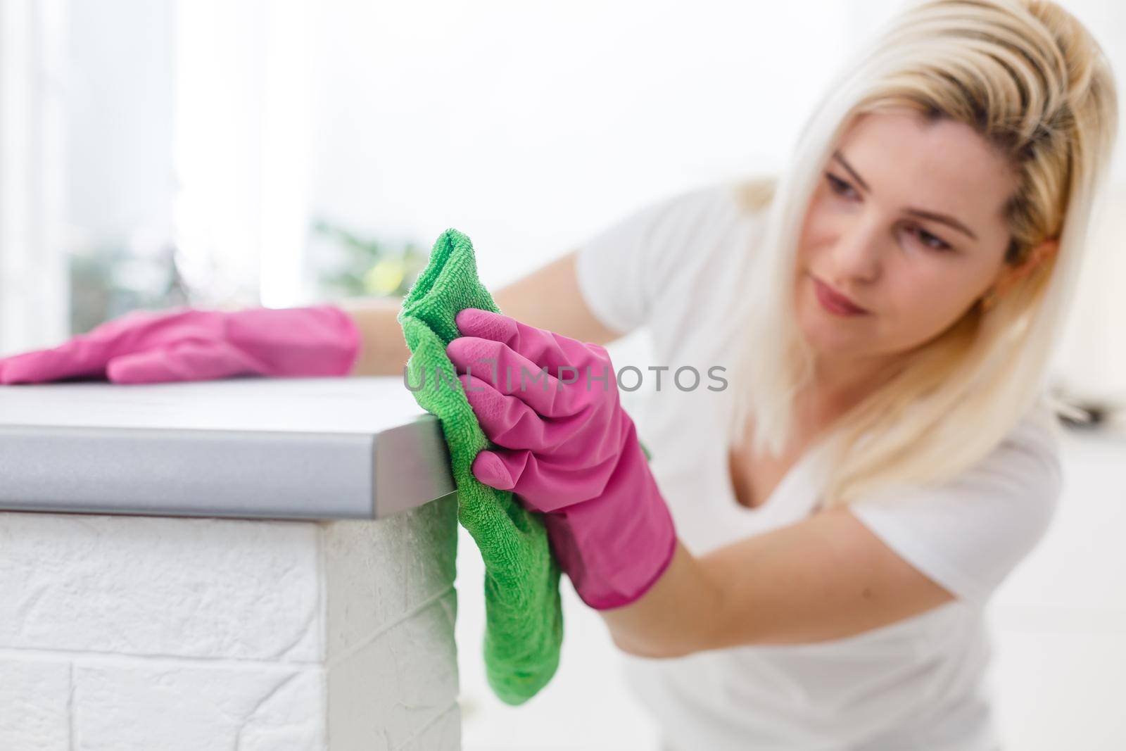 Cleanness is in trend. Pretty smiling woman wiping table with cloth and special means of washing by Andelov13