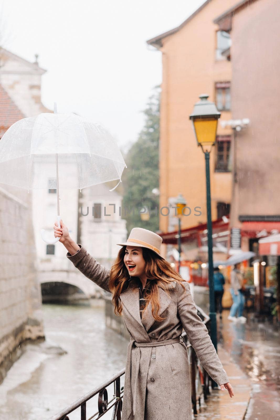 beautiful romantic girl in a coat and hat with a transparent umbrella in Annecy. France. The girl in the hat in France.