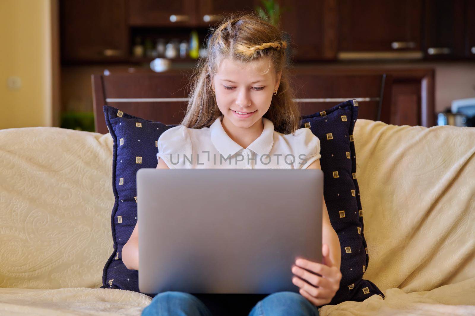 Child girl with laptop at home on the couch by VH-studio