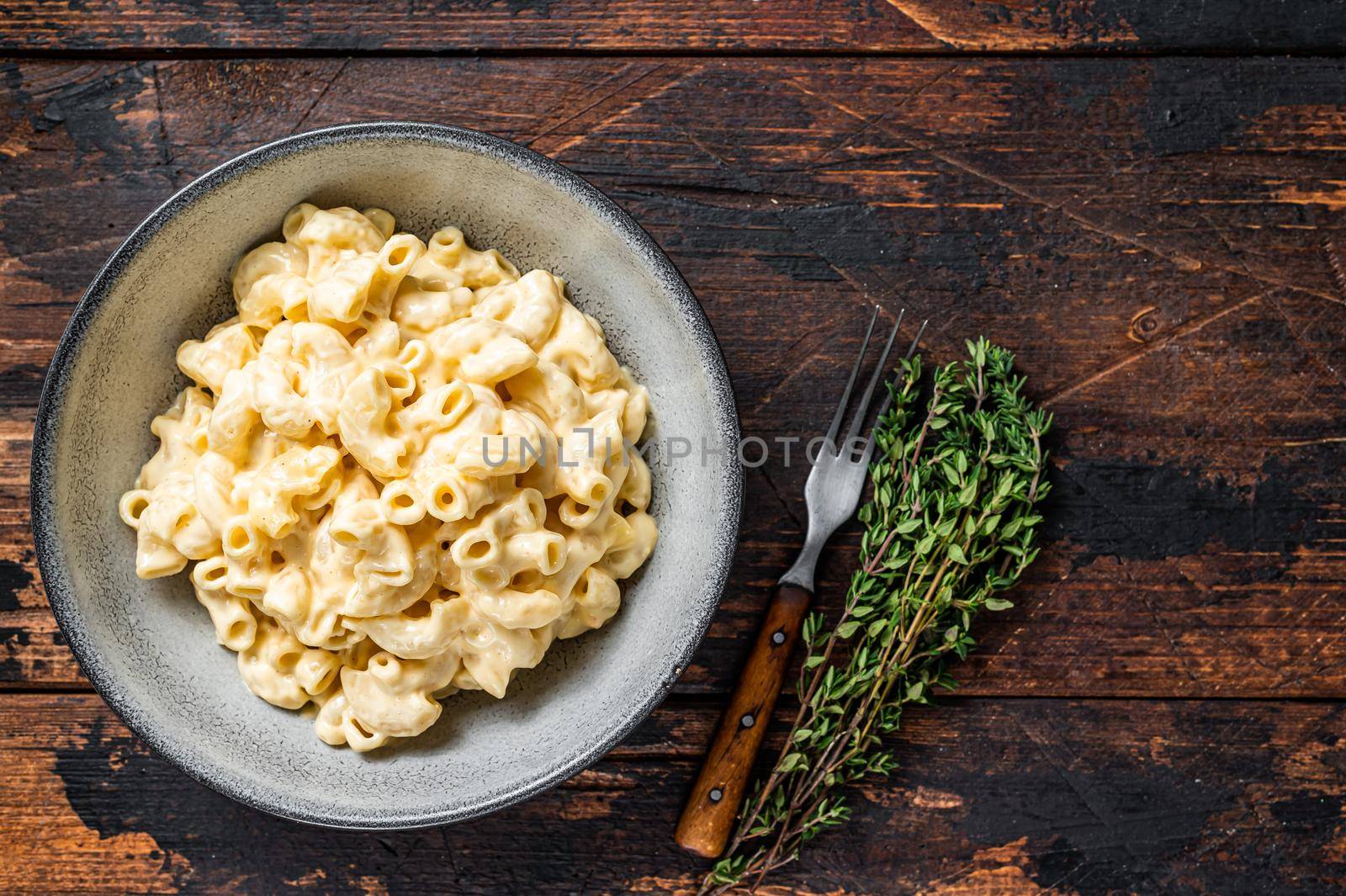 American dish Mac and cheese macaroni pasta with Cheddar. Dark wooden background. Top view. Copy space by Composter