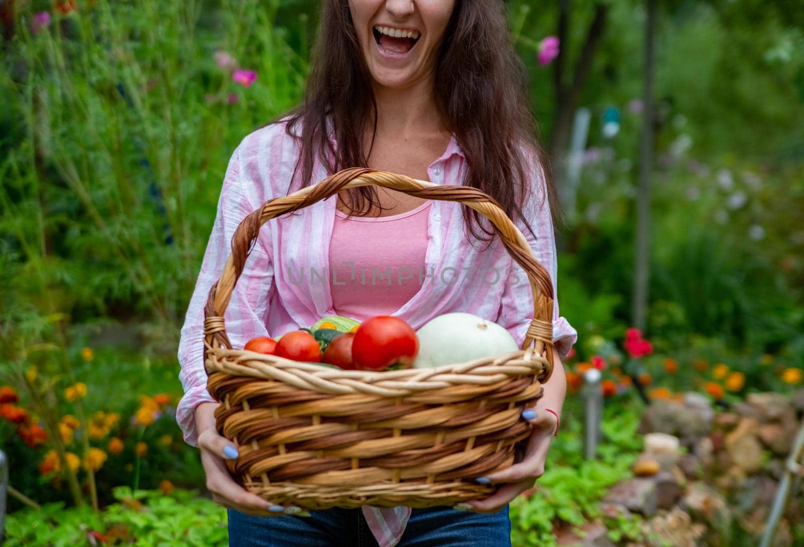 faceless happy smiling woman farmer holding a basket of vegetables from her vegetable garden. close up no face