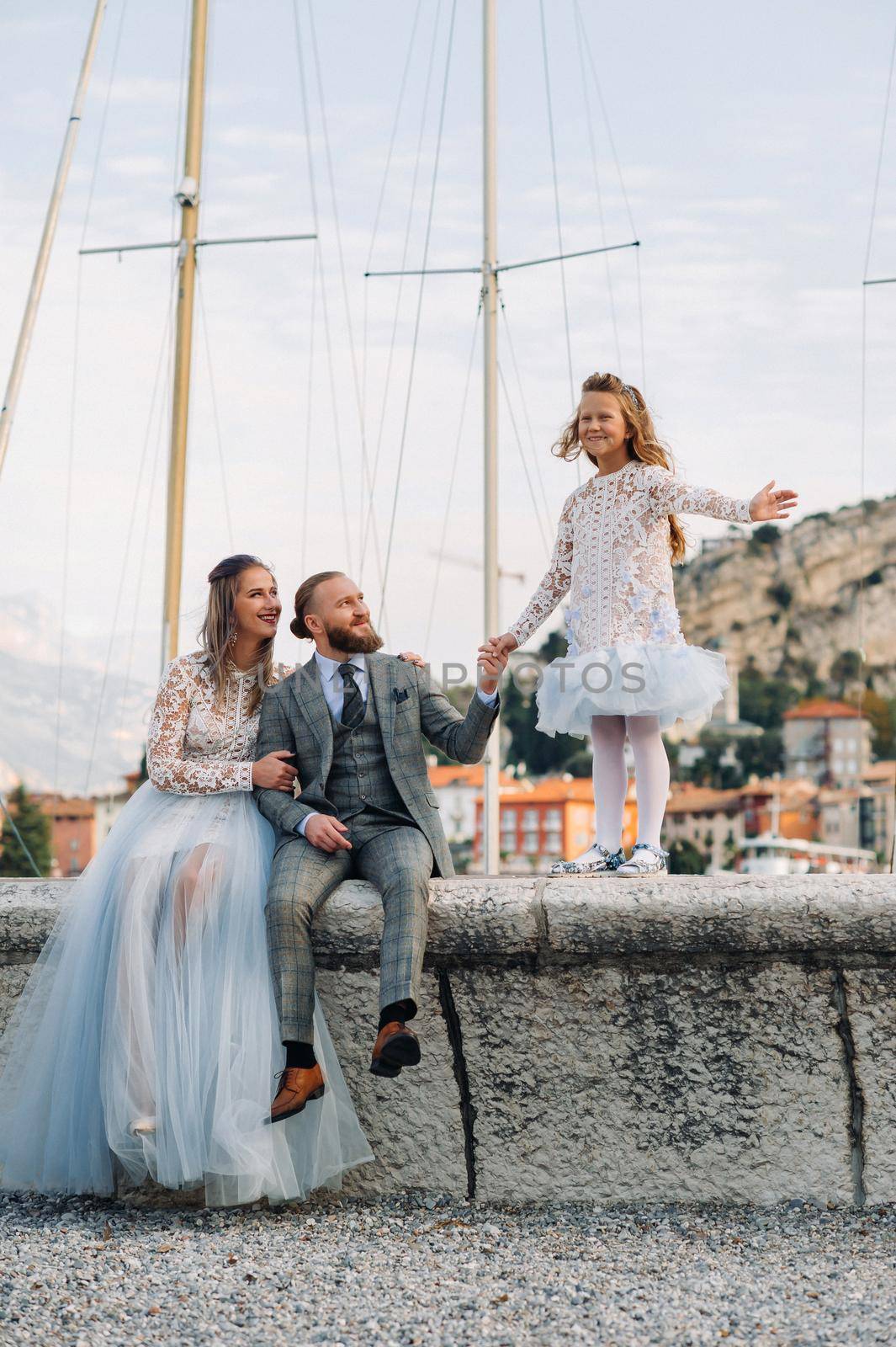 Italy, Lake Garda. Beautiful family on the shores of lake Garda in Italy at the foot of the Alps. Father, mother and daughter in Italy by Lobachad