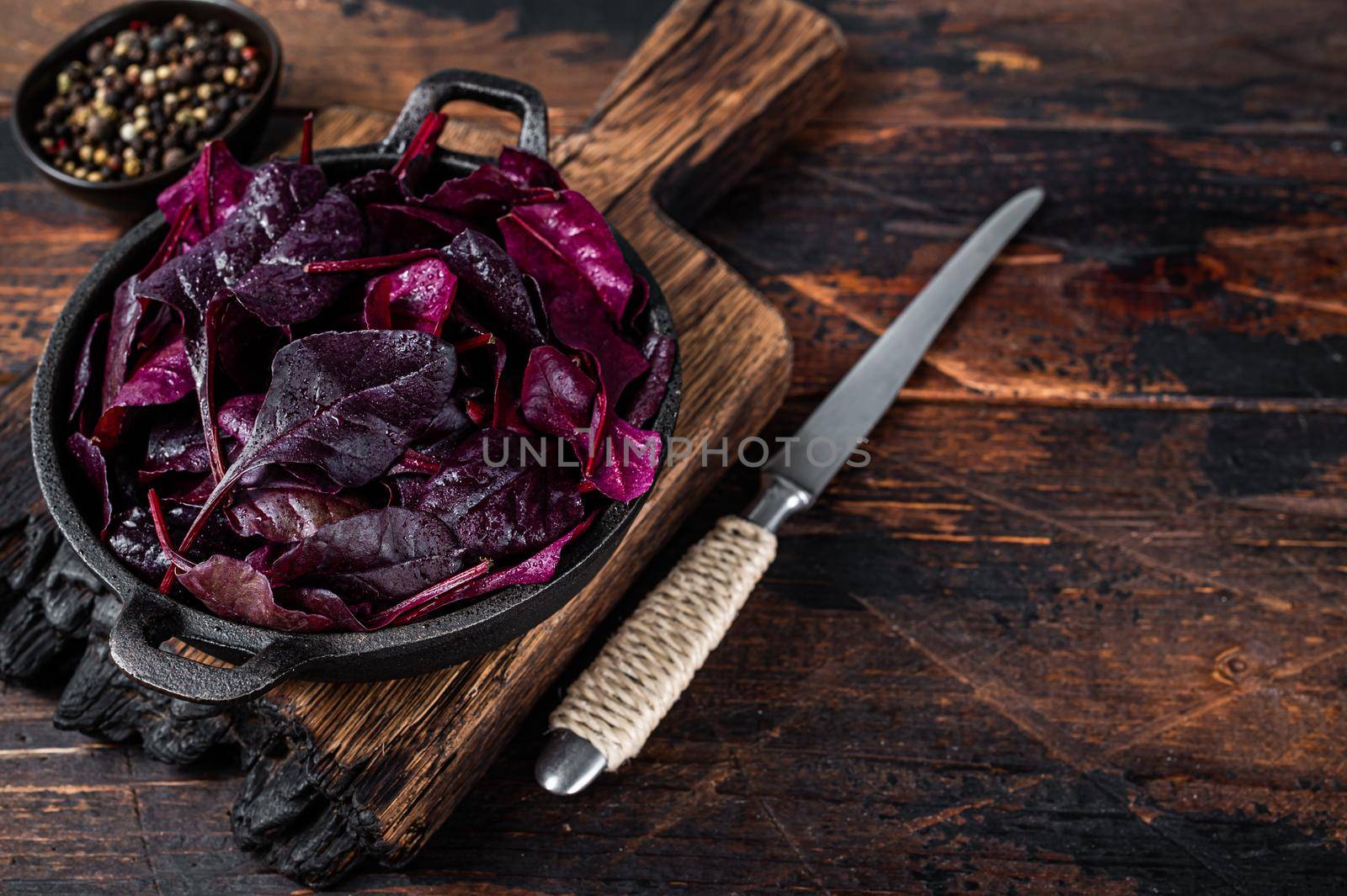 Swiss red chard or Mangold salad Leafs in a pan. Dark wooden background. Top view. Copy space.