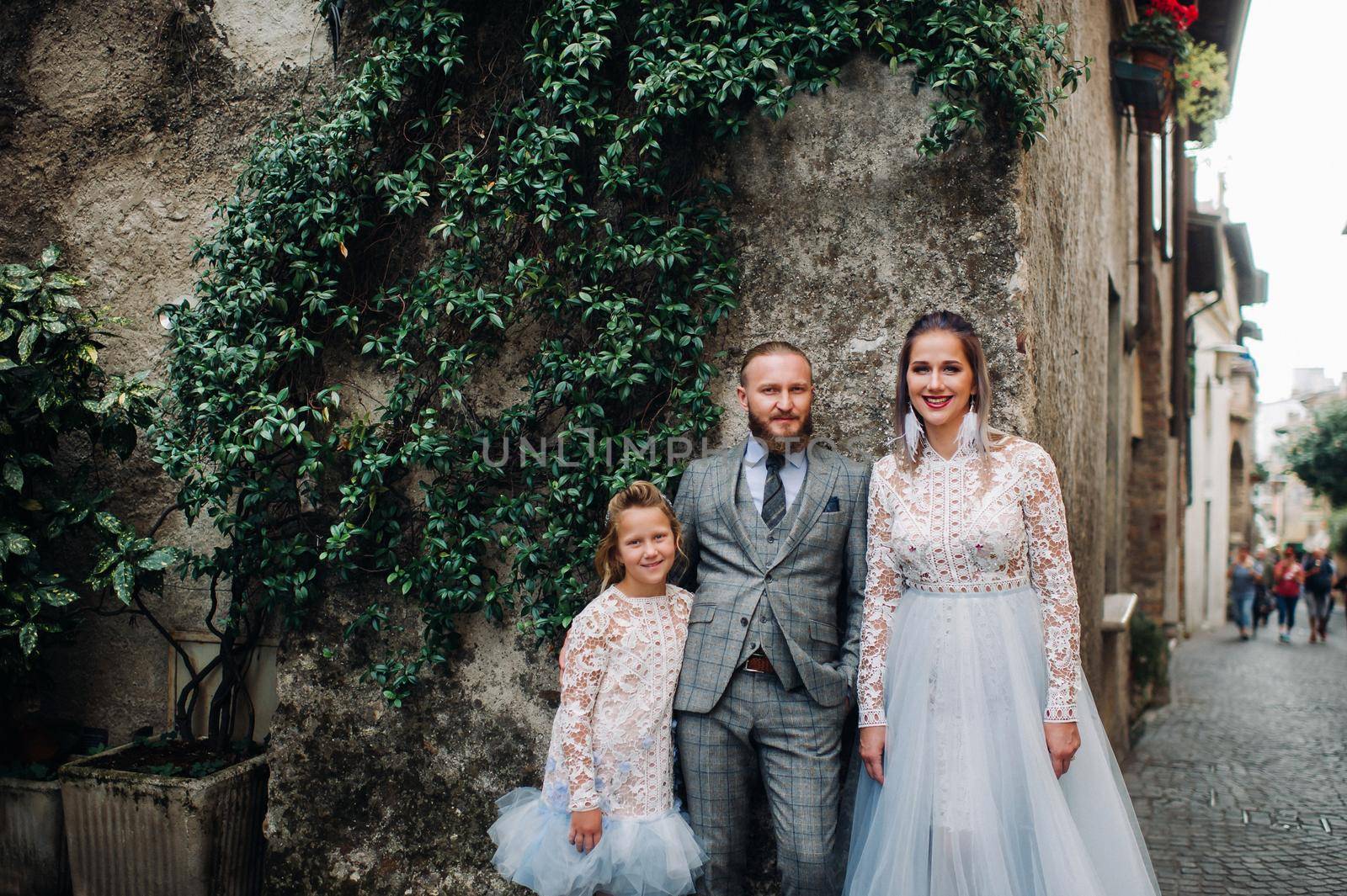 A happy young family walks through the old town of Sirmione in Italy.Stylish family in Italy on a walk by Lobachad