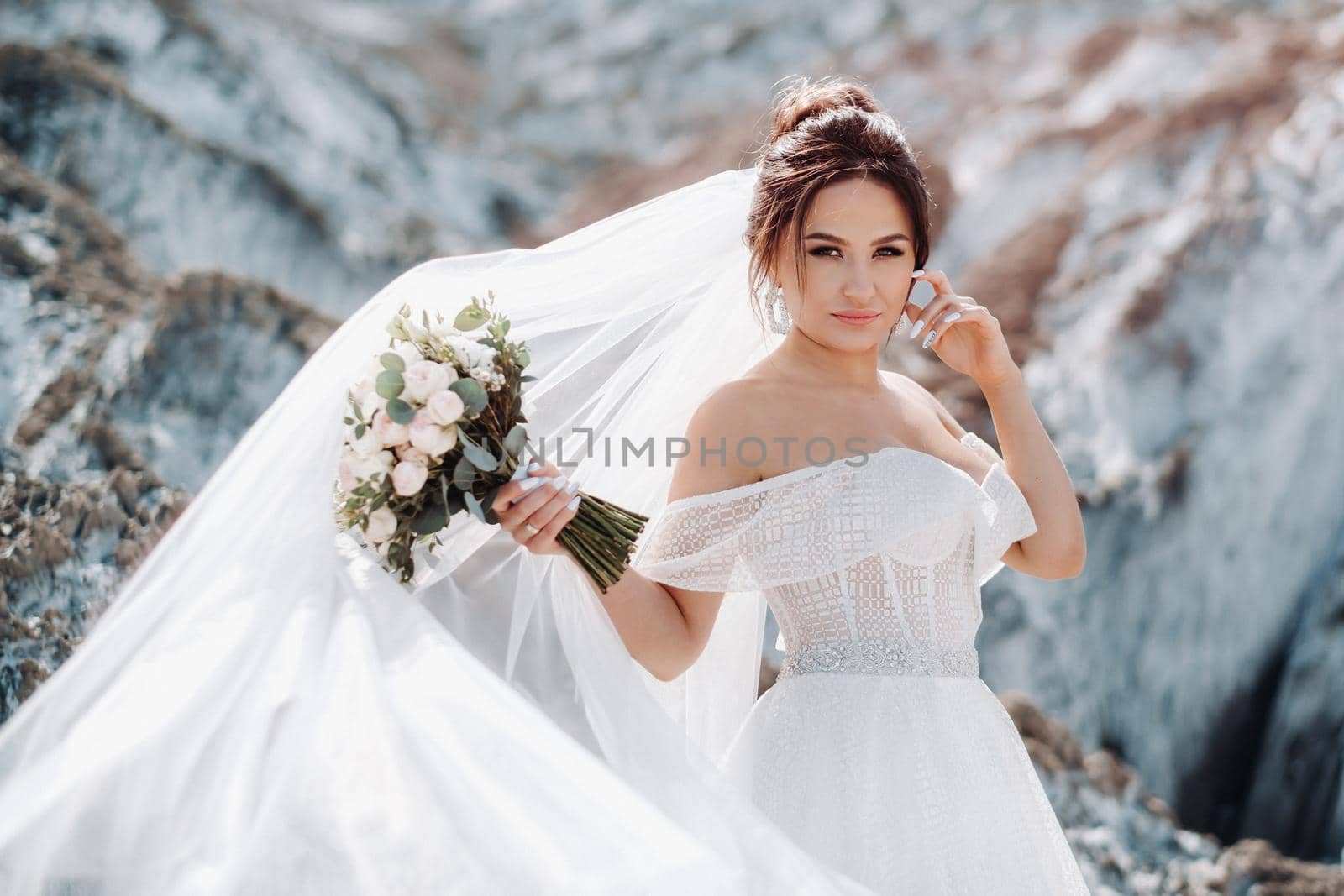 Beautiful bride in a wedding dress with a bouquet on the top of the salt mountains. A stunning young bride with curly hair . Wedding day. . Beautiful portrait of the bride without the groom