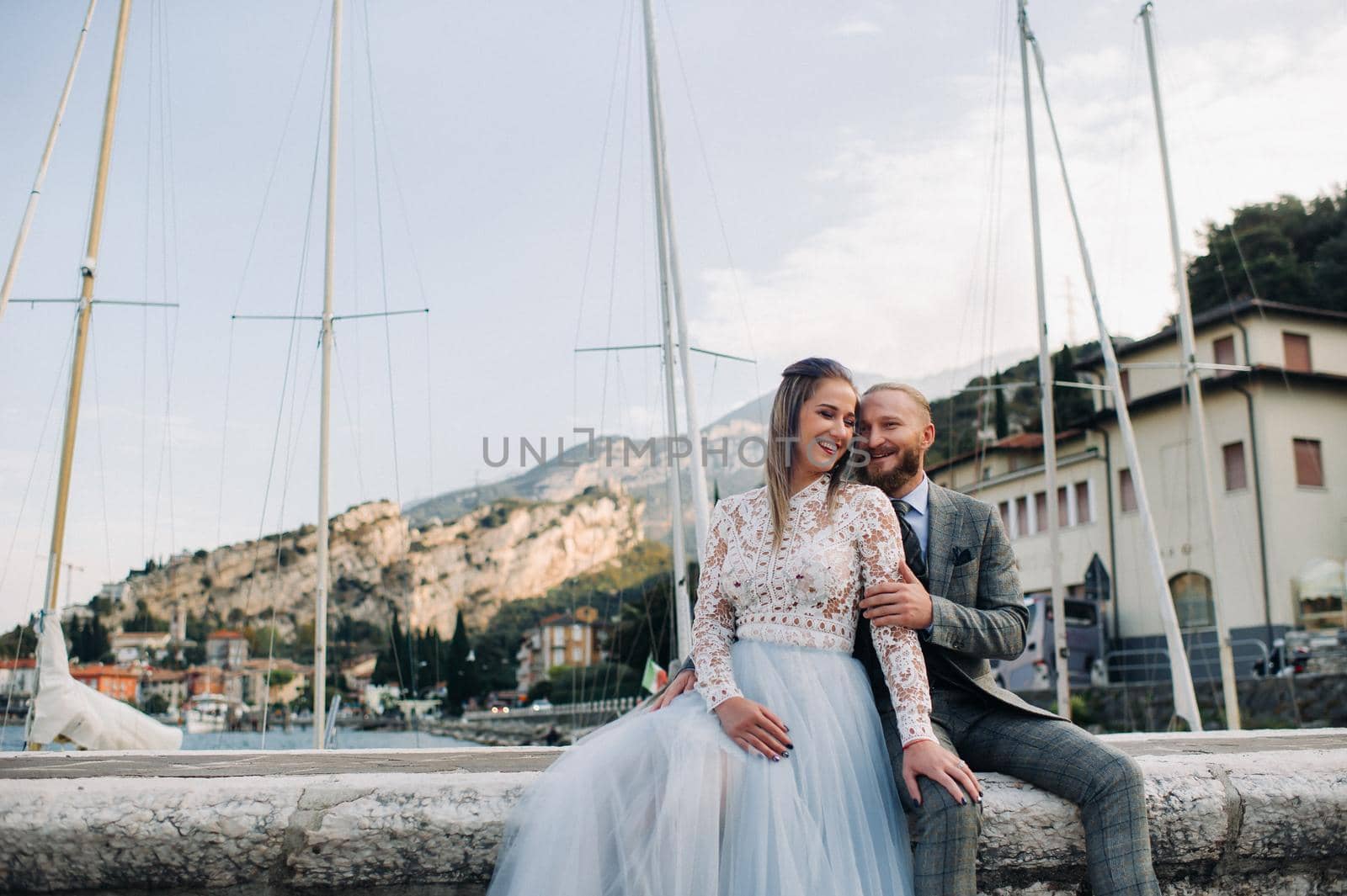 Italy, Lake Garda. A beautiful couple on the shores of lake Garda in Italy at the foot of the Alps.A man and a woman sit on a pier in Italy.