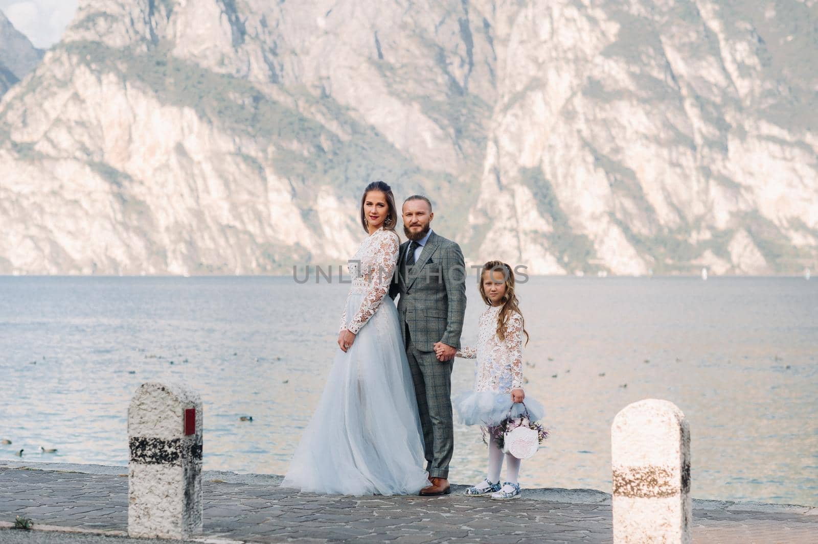 Italy, Lake Garda. Beautiful family on the shores of lake Garda in Italy at the foot of the Alps. Father, mother and daughter in Italy by Lobachad