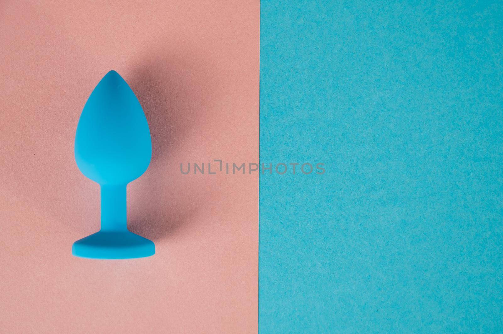 Blue anal plug on a pink background. Plastic sex toy for alternative sex. Copy space. by mrwed54