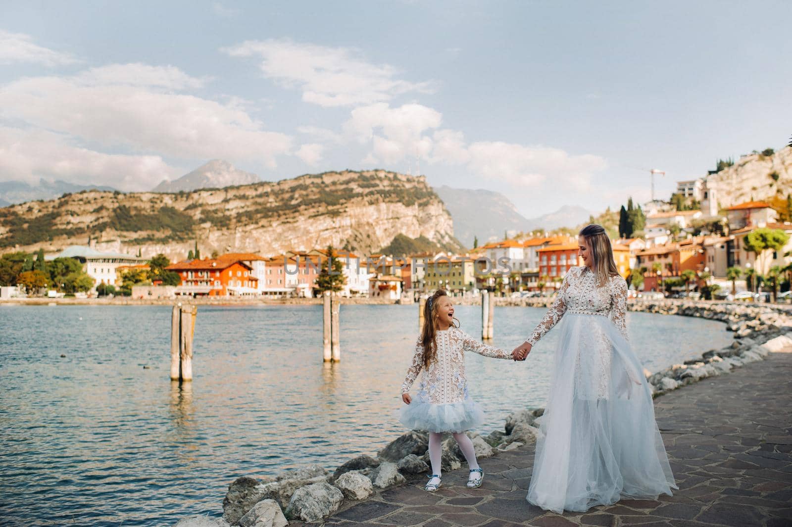 Italy, Lake Garda.Stylish Mother and daughter on the shores of lake Garda in Italy at the foot of the Alps. mother and daughter in Italy by Lobachad