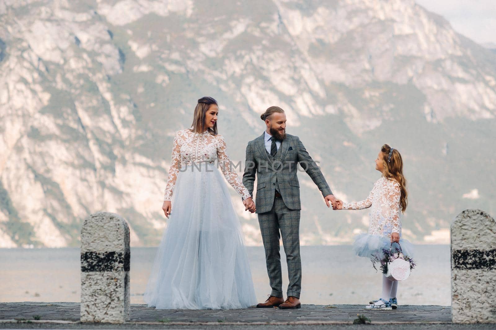 Italy, Lake Garda. Beautiful family on the shores of lake Garda in Italy at the foot of the Alps. Father, mother and daughter in Italy.