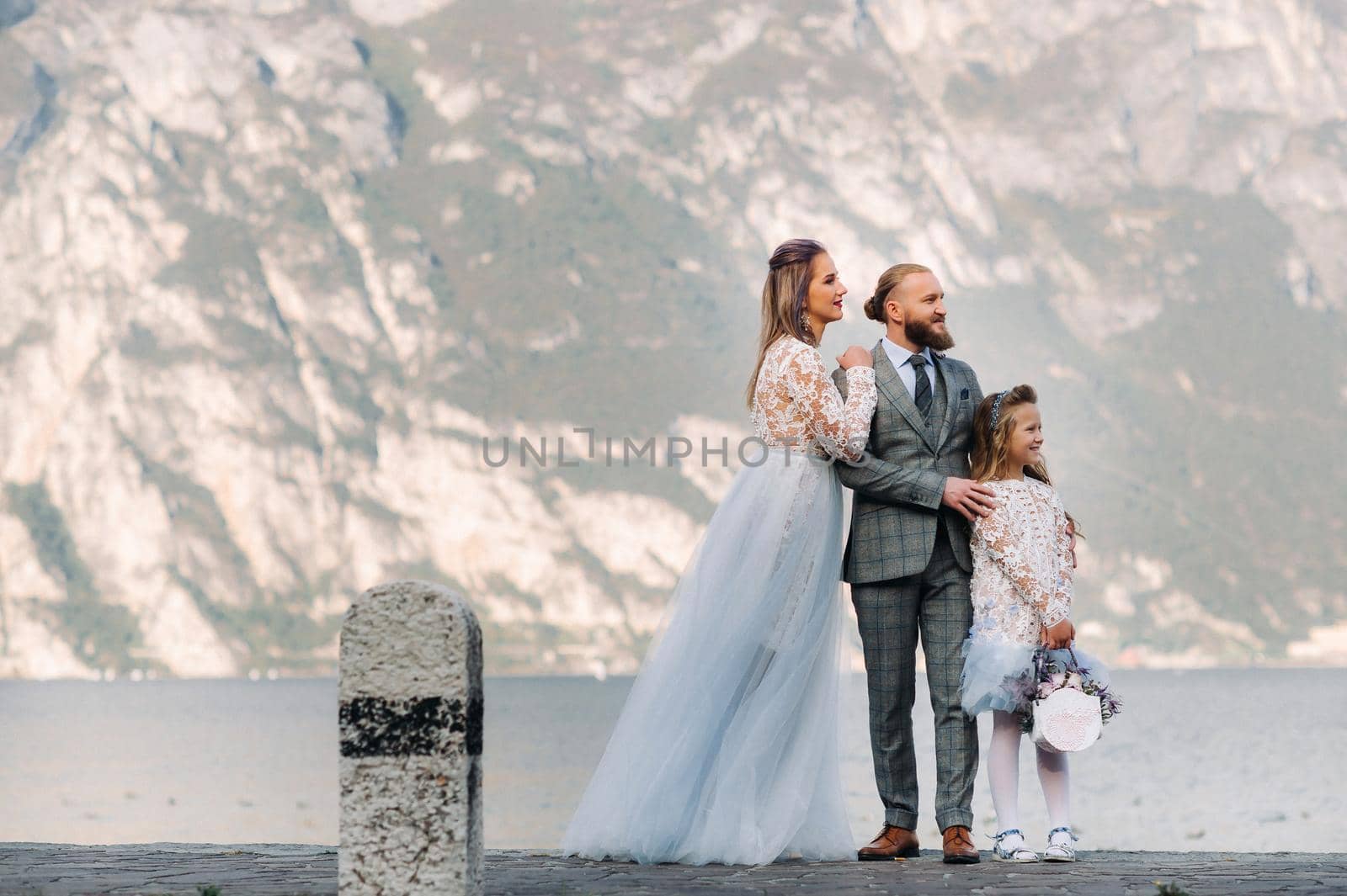 Italy, Lake Garda. Beautiful family on the shores of lake Garda in Italy at the foot of the Alps. Father, mother and daughter in Italy by Lobachad