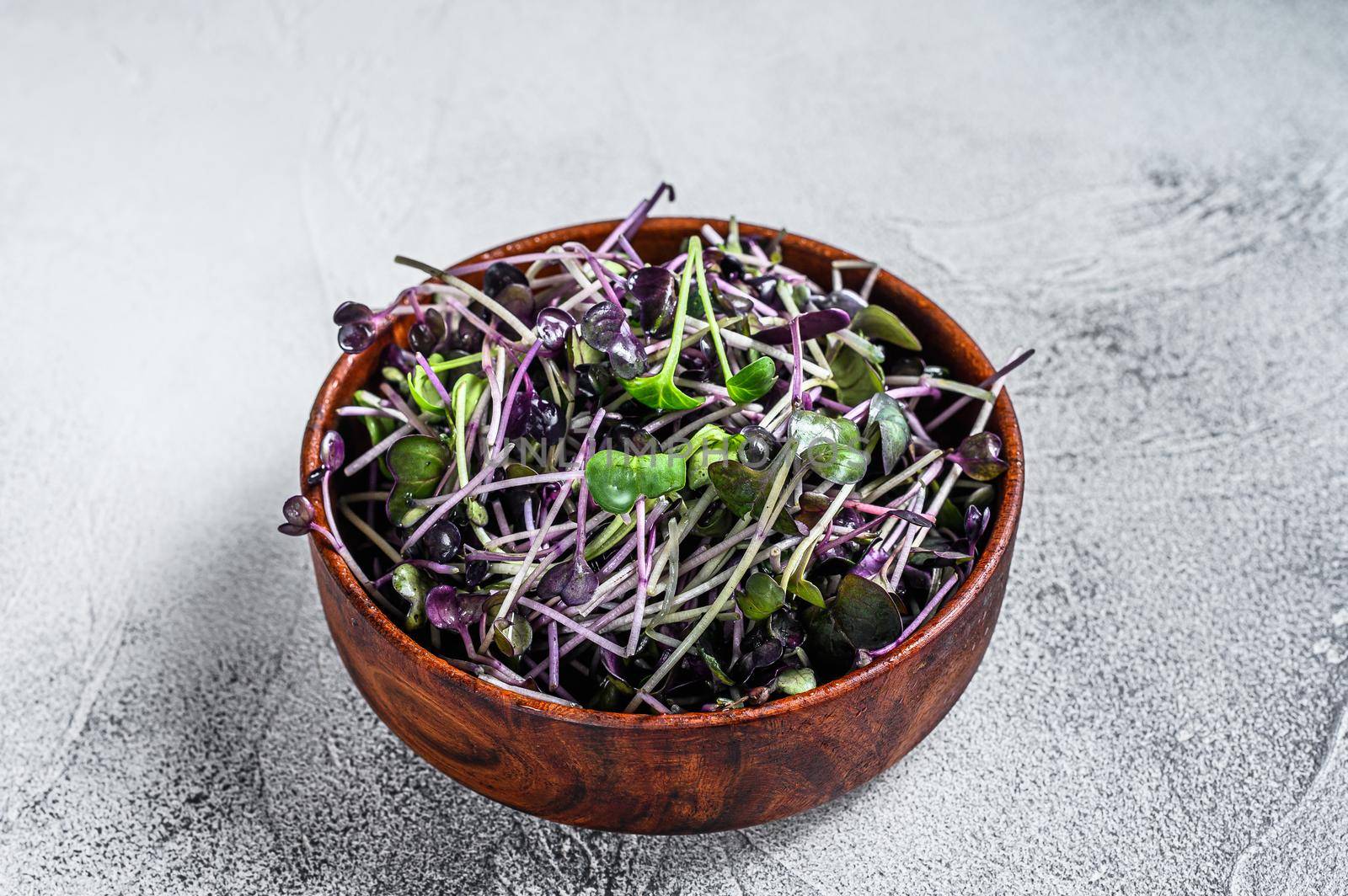 Microgreen radish cress sprouts in a wooden bowl. White background. Top view.