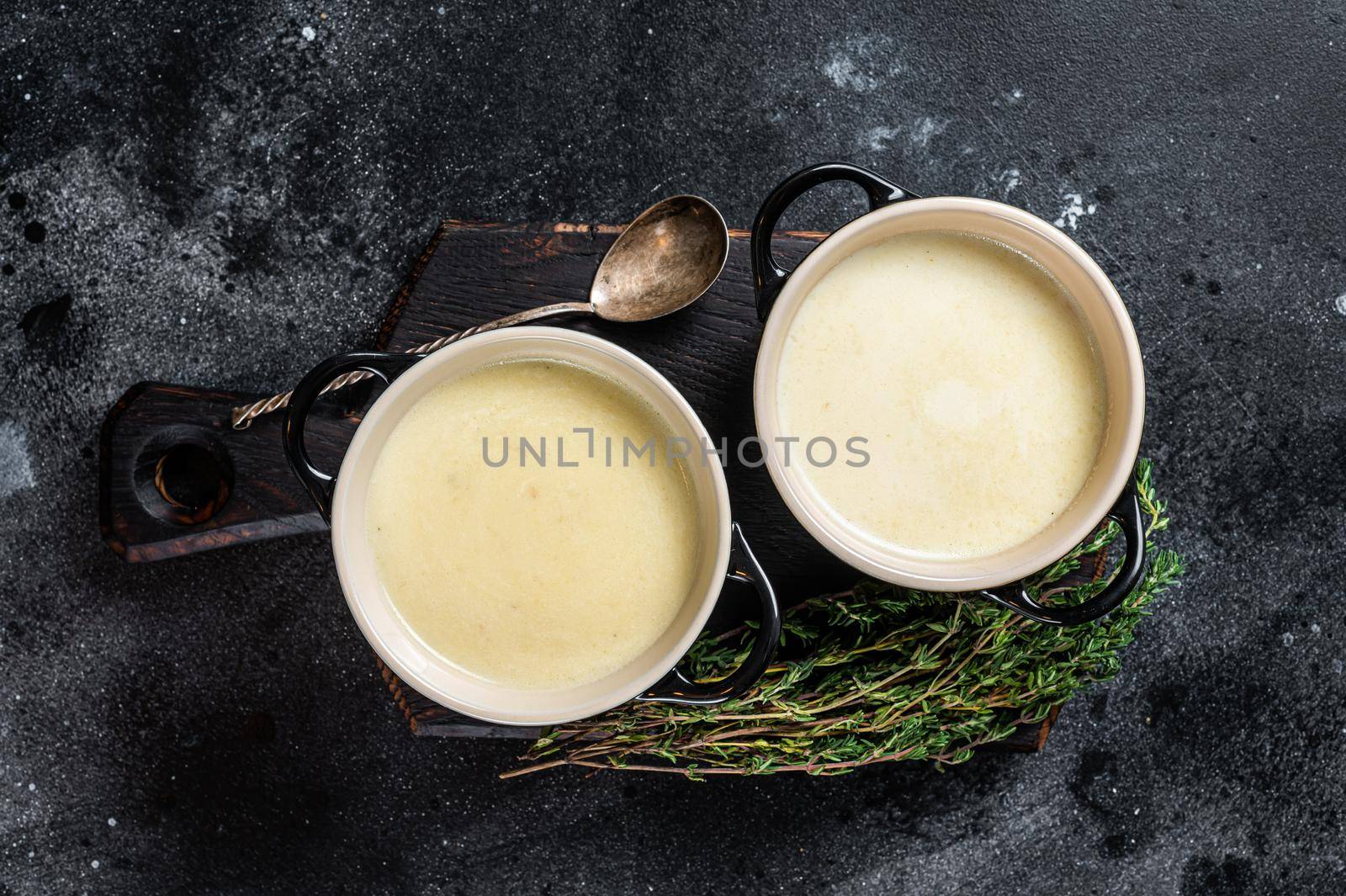 Potato cream soup in bowls on kitchen table. Black background. Top view.