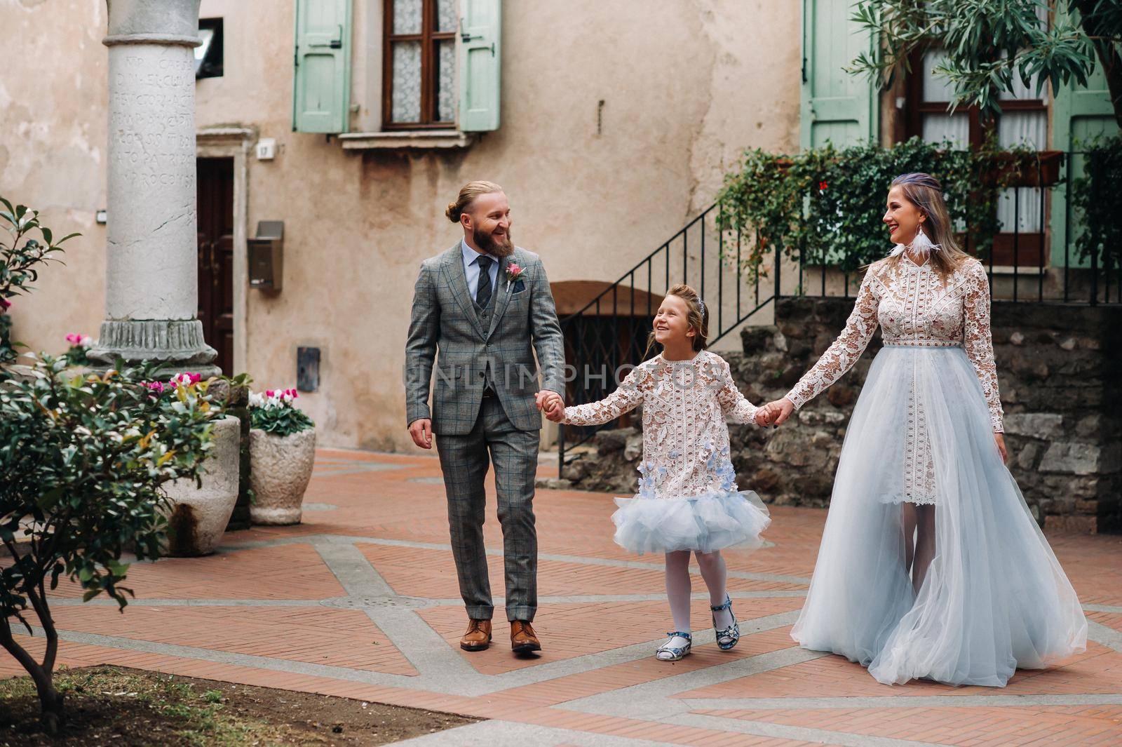 A happy young family walks through the old town of Sirmione in Italy.Stylish family in Italy on a walk by Lobachad