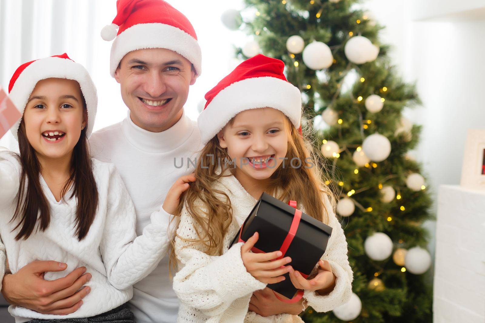 happy family father mother and children sitting by fireplace on Christmas Eve by Andelov13