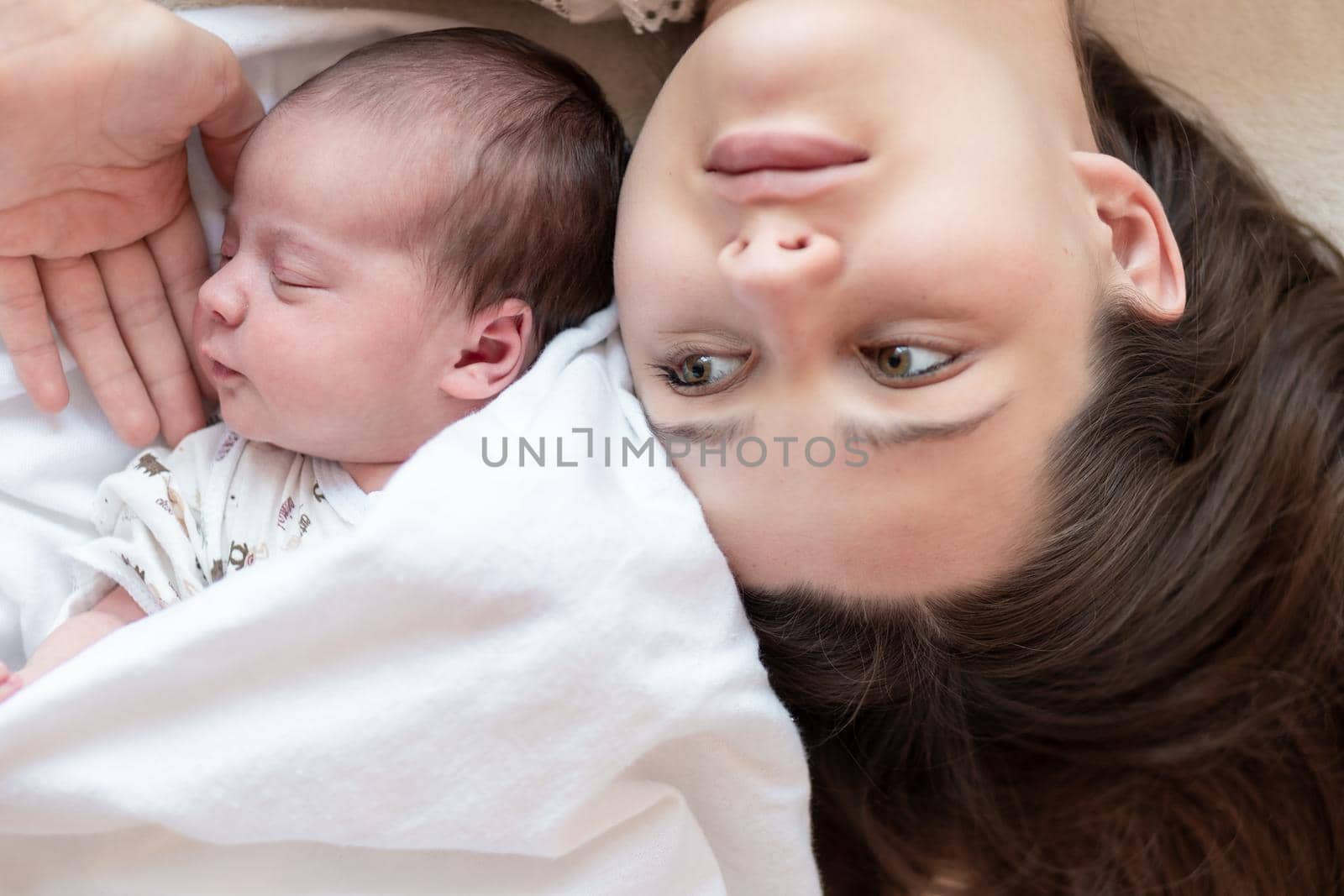 motherhood, infancy, childhood, family, care, medicine, sleep, health, maternity concept - portrait of mom with newborn baby wrapped in diaper on white background, place for text, close-up, soft focus by mytrykau