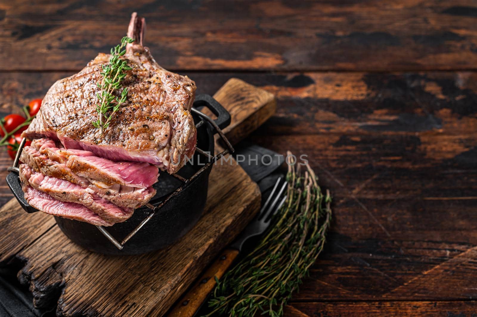 Grilled Tomahawk rib eye steak on grill with herbs. Wooden background. Top view. Copy space.