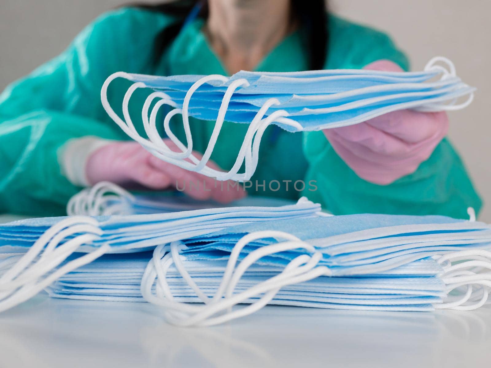 Close-up of women's hands in disposable gloves counting medical masks during the pandemic.