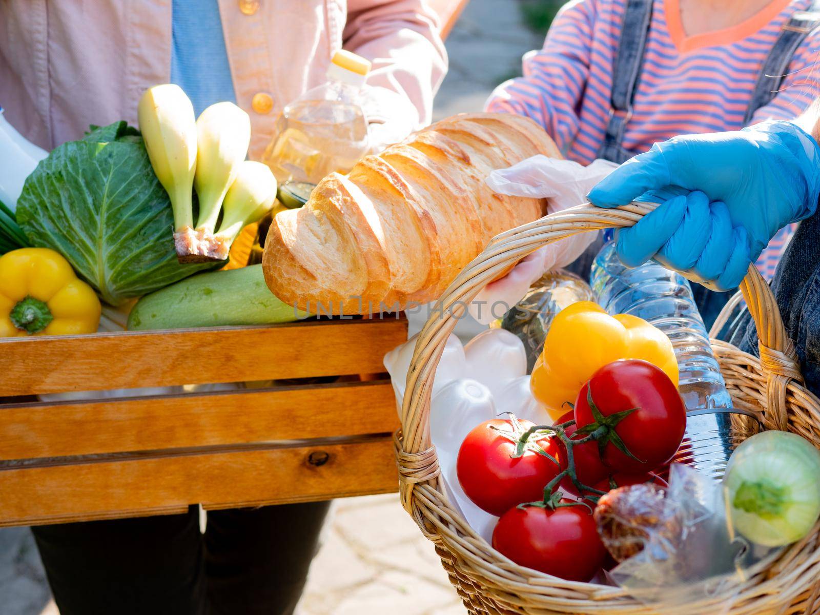 A family of volunteers in medical gloves hold food packages for unprotected segments of the population during the coronavirus pandemic. by Utlanov