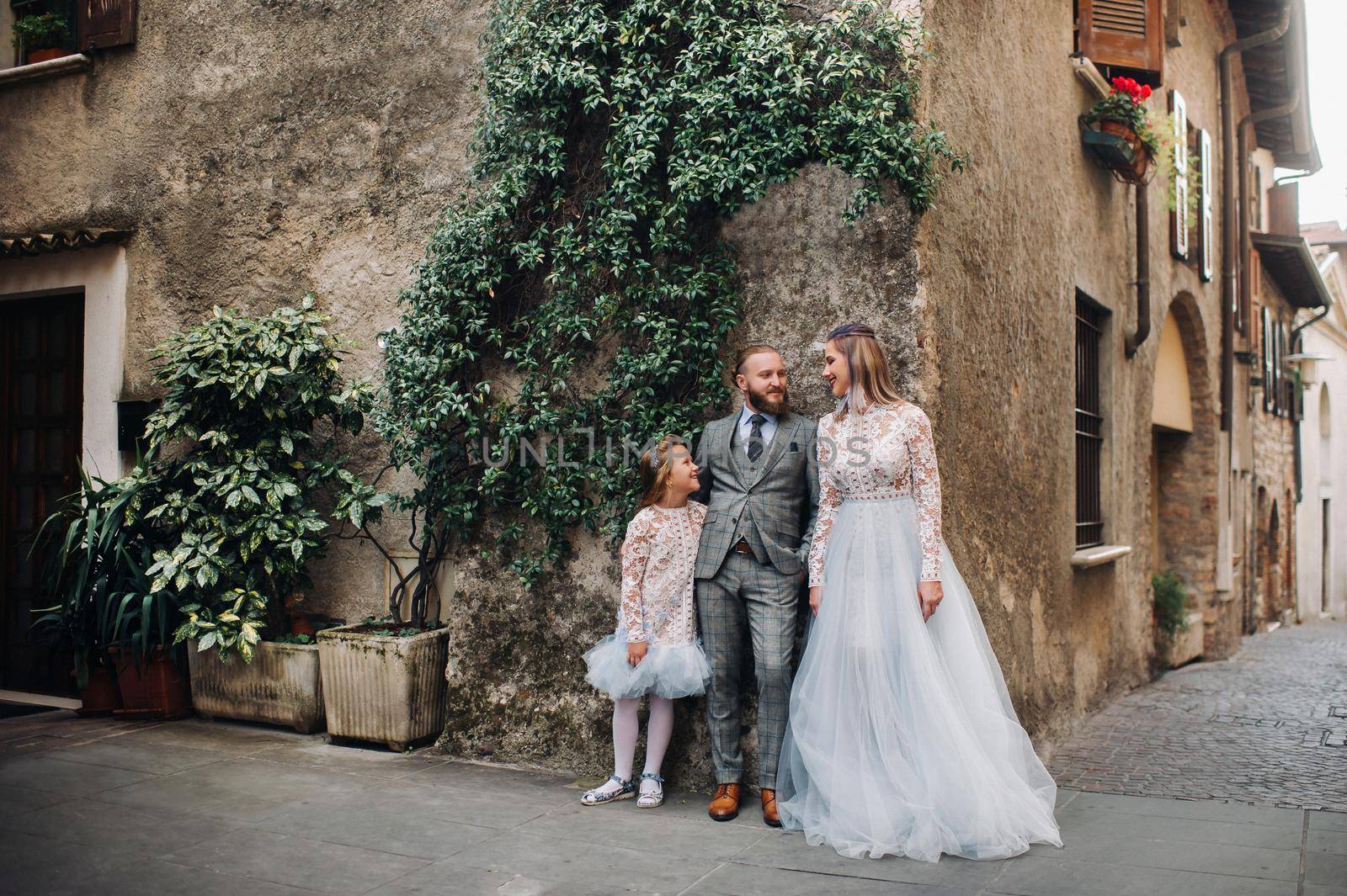 A happy young family walks through the old town of Sirmione in Italy.Stylish family in Italy on a walk.