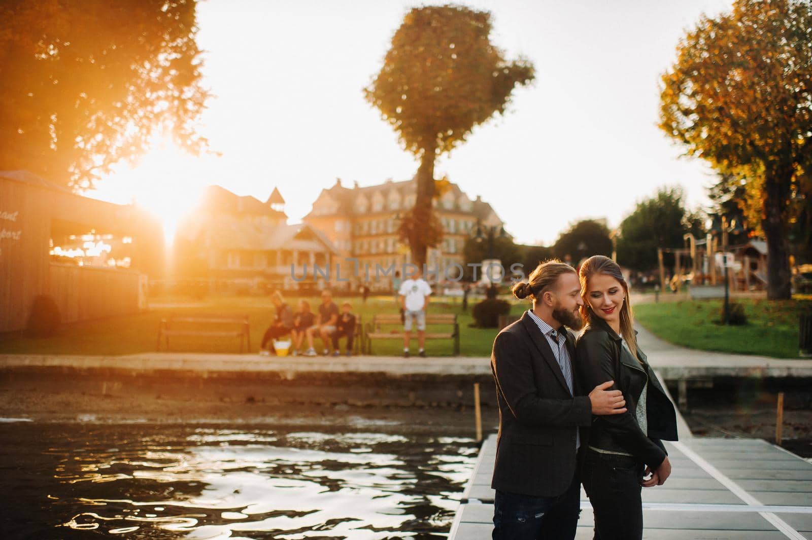 a family of two stands on a pier in Austria's old town at sunset .A man and a woman embrace on the embankment of a small town in Austria.Europe.Felden am Werten see.