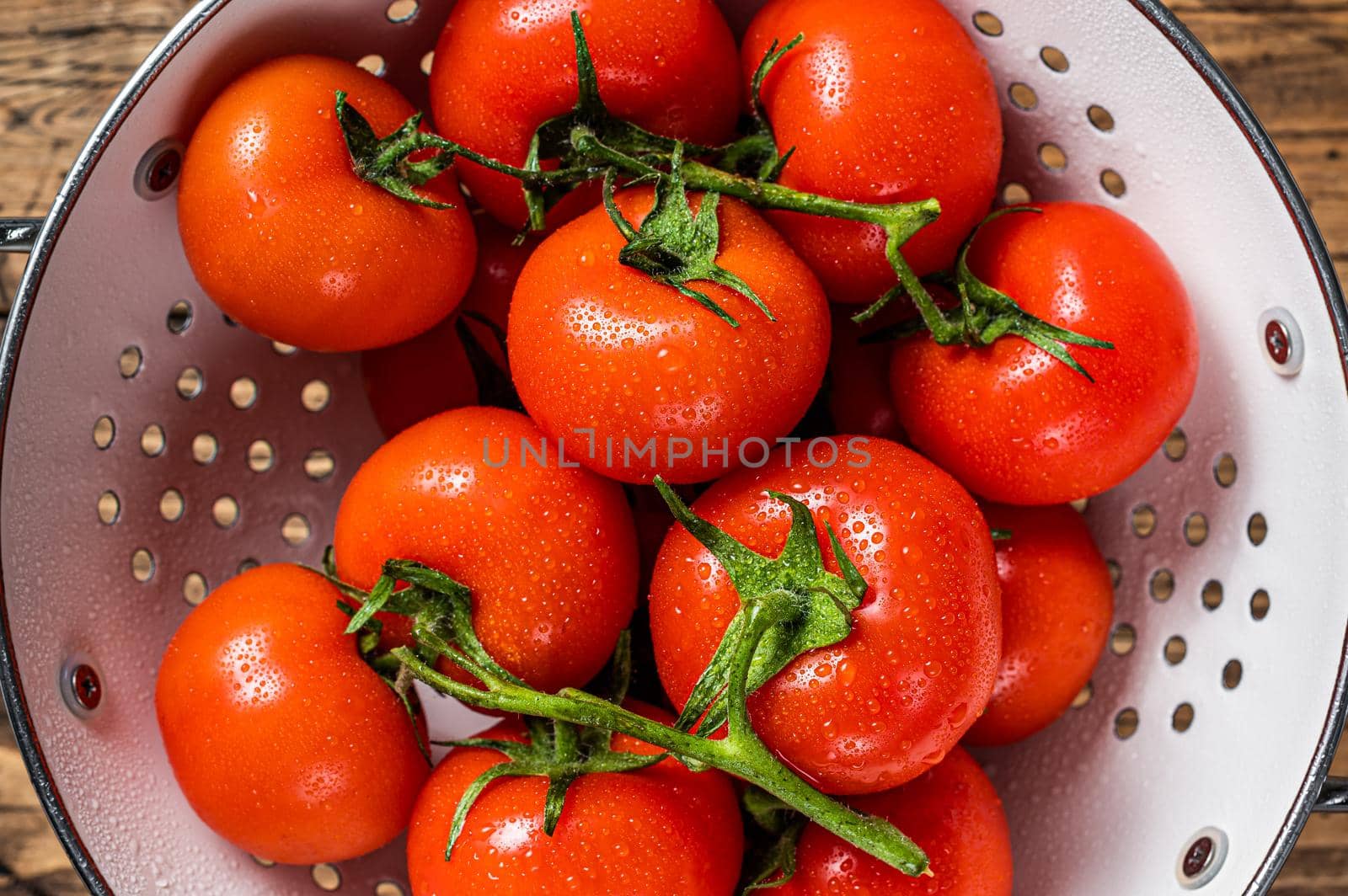 Branch of Red cherry tomatoes in colander. Wooden background. Top view by Composter