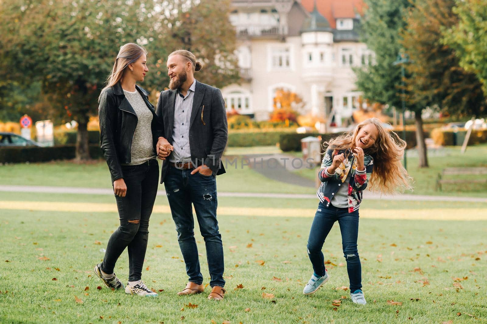 A happy family of three runs through the grass in Austria's old town.A family walks through a small town in Austria.Europe.Velden am werten Zee.