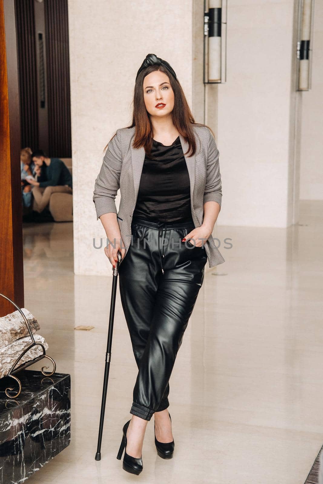 A girl in black trousers and a jacket with a cane in the interior.