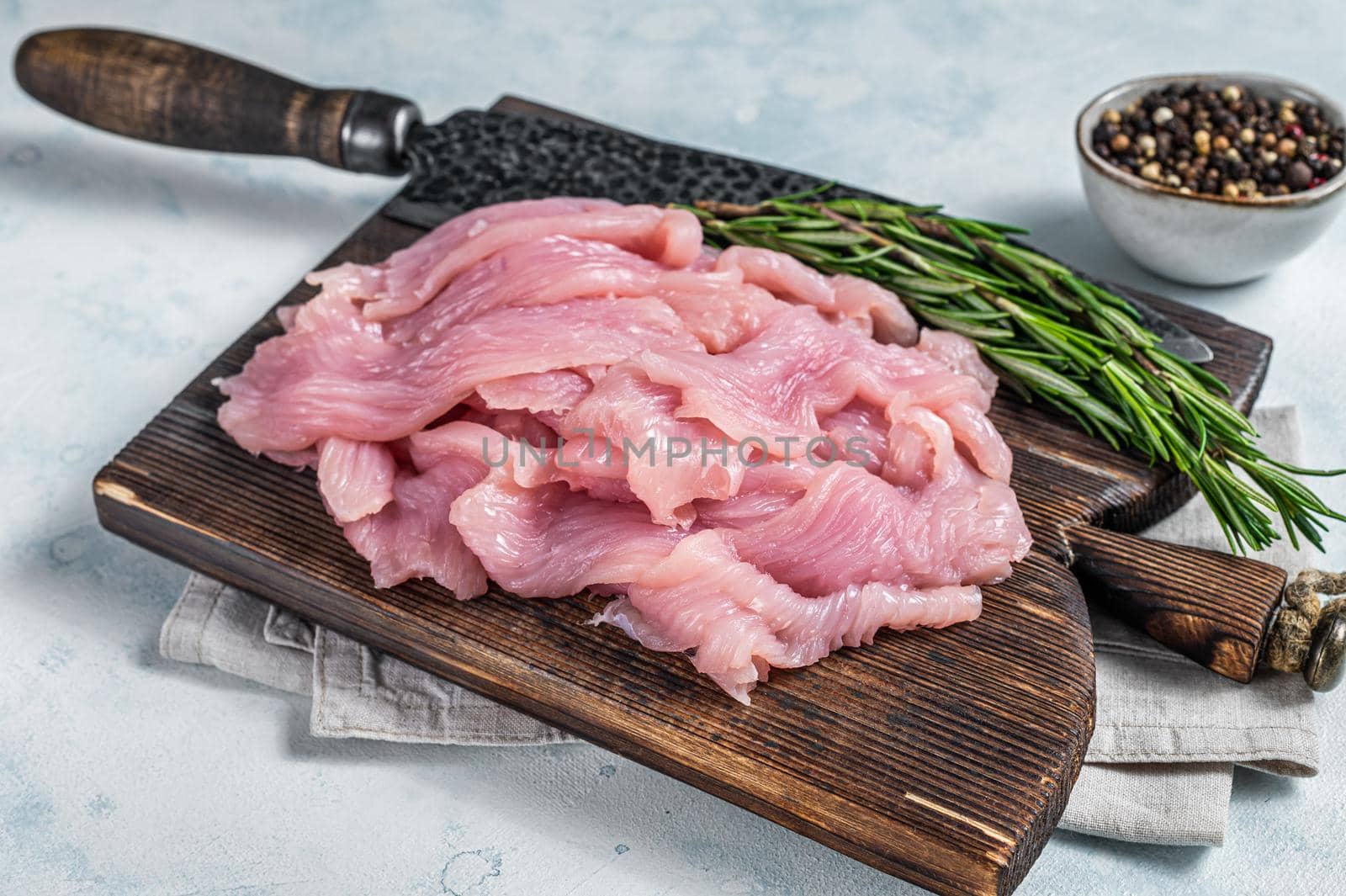 Sliced Raw turkey or chicken fillet meat on a cutting board with butcher knife. White background. Top View.